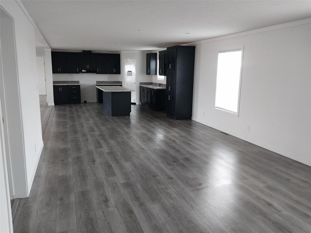 Kitchen with dark cabinets, light countertops, dark wood finished floors, a center island, and ornamental molding