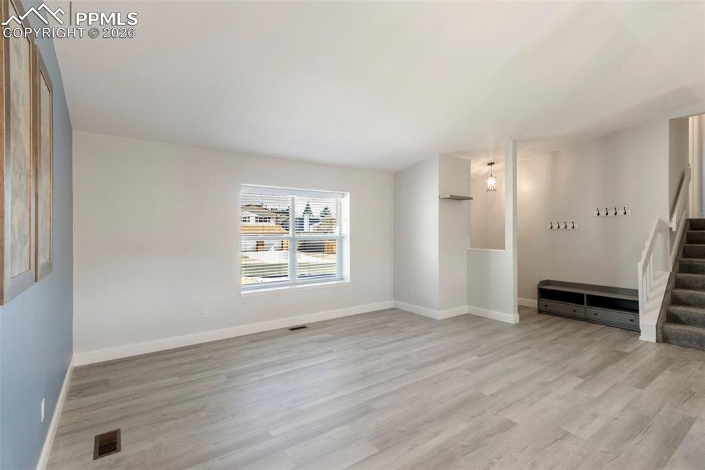 Formal Living Room with vaulted ceiling and light colored plank LVT flooring looking toward front entrance/foyer