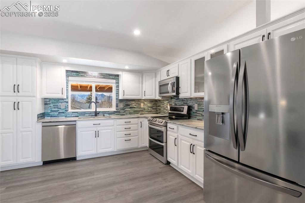 Kitchen with stainless steel appliances includes a double-oven range, white cabinets, light colored stone countertops, tasteful backsplash, under cabinet and recessed lighting.  Standing at the kitchen sink, you'll be treated with full views of Pikes Peak!!
