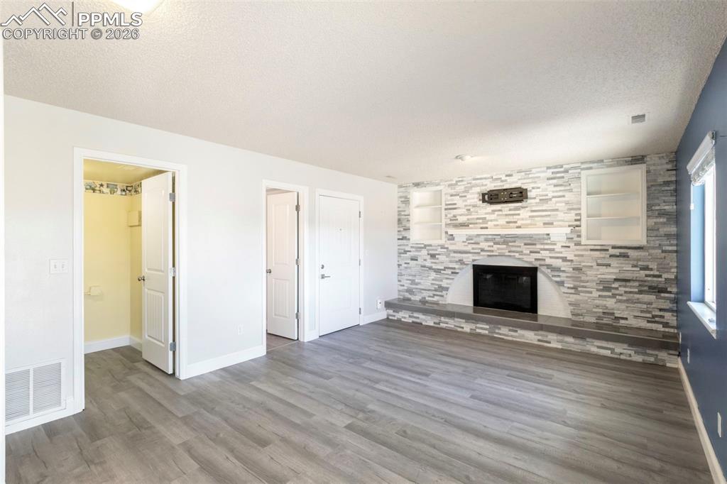 Family Room with built in features, LVT flooring, stone surround fireplace, laundry room, half bath, and access to oversized 2-car garage