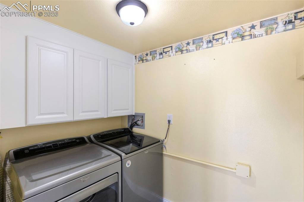 Laundry area featuring washer and dryer, cabinet space, and LVT flooring