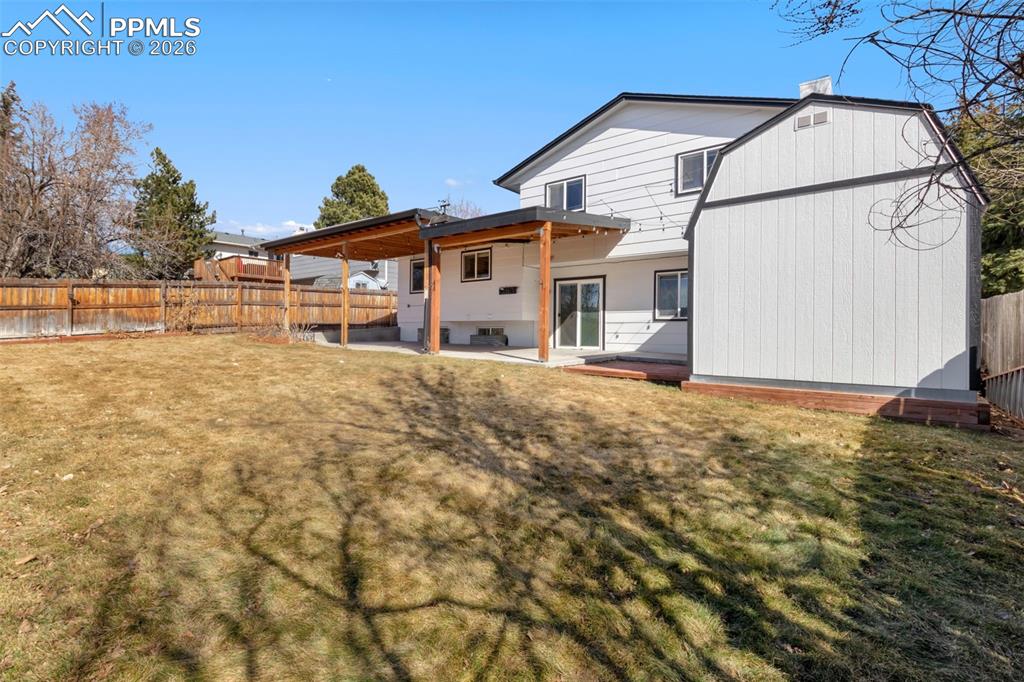 Back of house featuring a covered patio, a fenced backyard, and a large shed