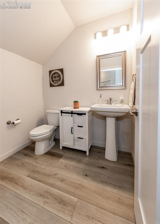 Half bathroom with vaulted ceiling and light wood-type flooring