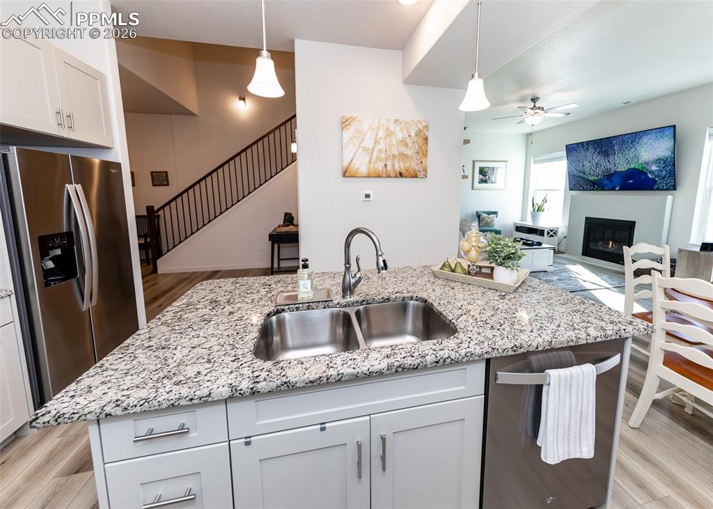 Kitchen with white cabinetry, stainless steel appliances, a kitchen island with sink, and ceiling fan