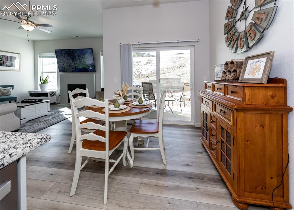 Dining space featuring a ceiling fan, light wood-style floors, and a fireplace
