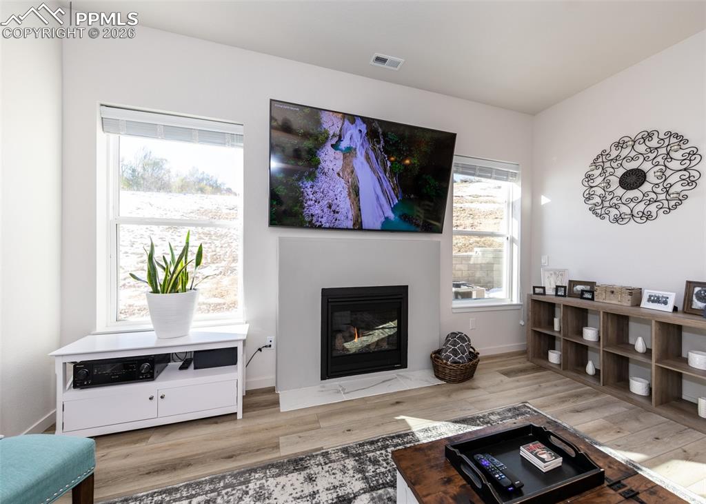 Living room with light wood-style flooring and a fireplace with flush hearth