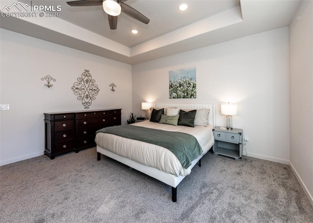 Bedroom with a raised ceiling, carpet floors, ceiling fan, and recessed lighting
