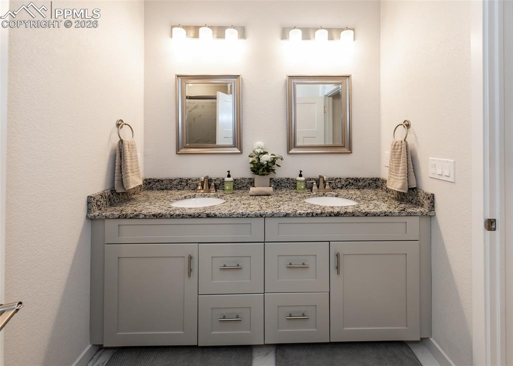 Bathroom featuring double vanity and a textured wall