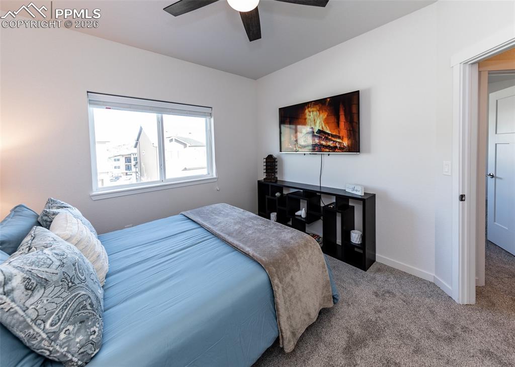 Carpeted bedroom with ceiling fan and baseboards