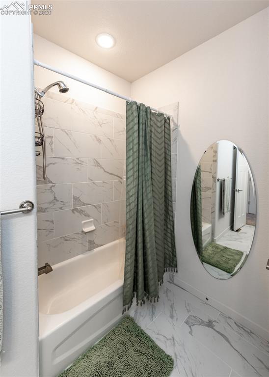 Bathroom with shower / bath combination with curtain and light marble finish flooring