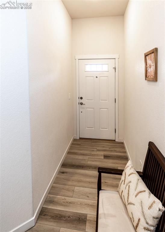 Doorway to outside with wood finished floors and baseboards