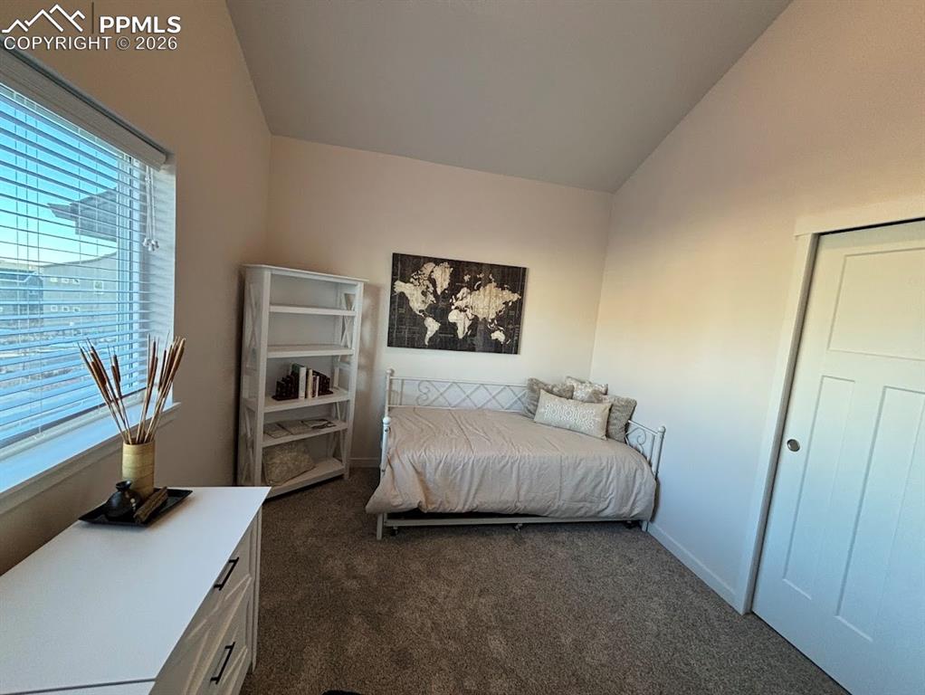 Bedroom with vaulted ceiling and dark carpet