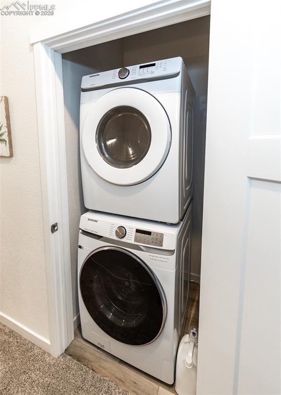 Laundry area featuring stacked washer / drying machine and baseboards