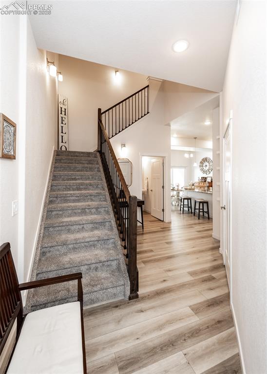 Stairs featuring wood finished floors, a high ceiling, and recessed lighting