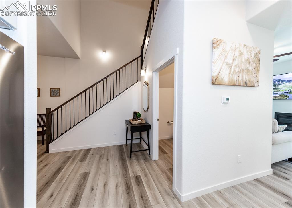 Staircase with wood finished floors, a glass covered fireplace, and a high ceiling