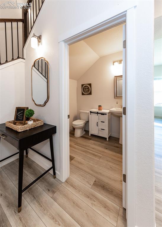 Half bathroom with light wood-style floors and vaulted ceiling