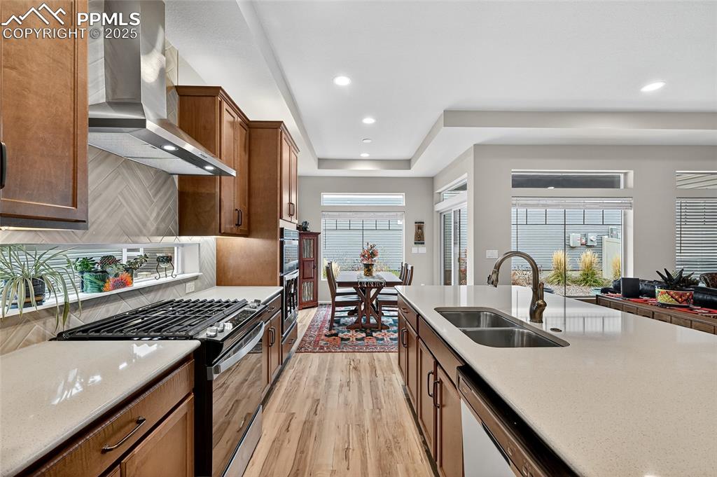Kitchen featuring range with gas stovetop, light wood-type flooring, light stone counters, decorative backsplash, and recessed lighting