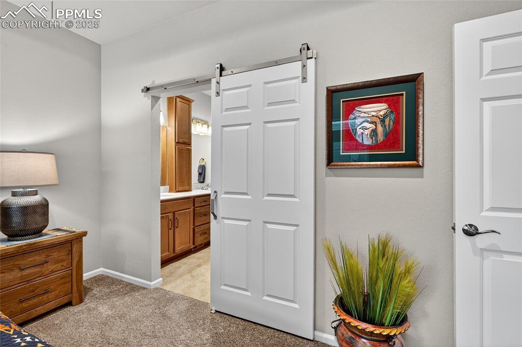 Bedroom with ensuite bath, light carpet, and a barn door