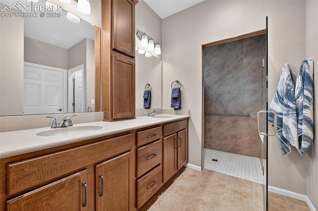 Bathroom with double vanity, light tile patterned floors, a stall shower, and a textured wall