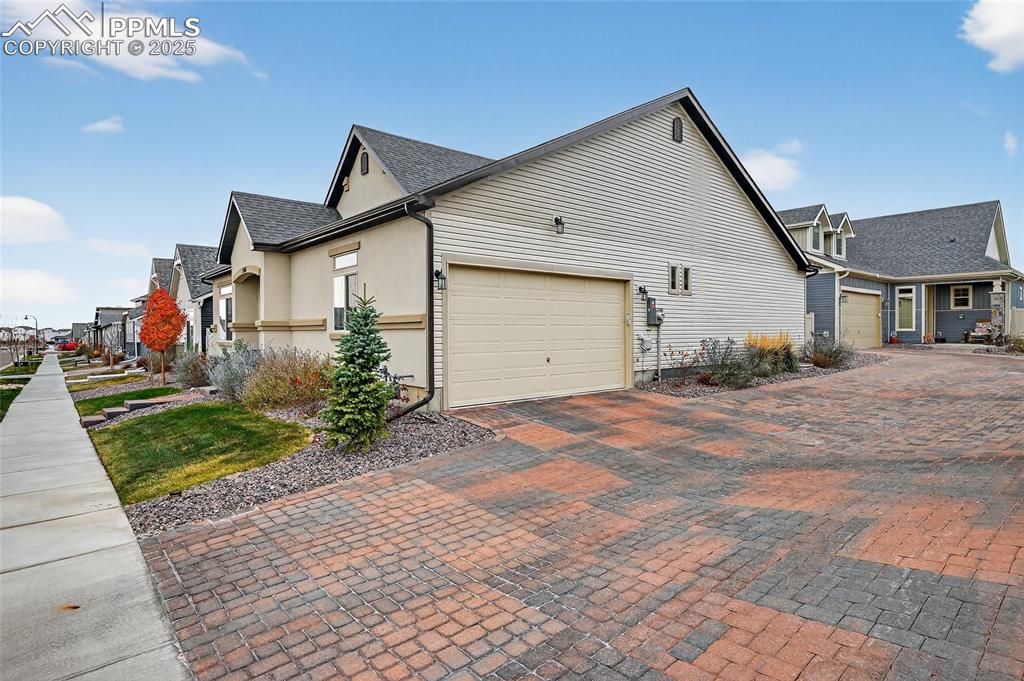 View of side of home featuring a garage, a residential view, driveway, and a shingled roof