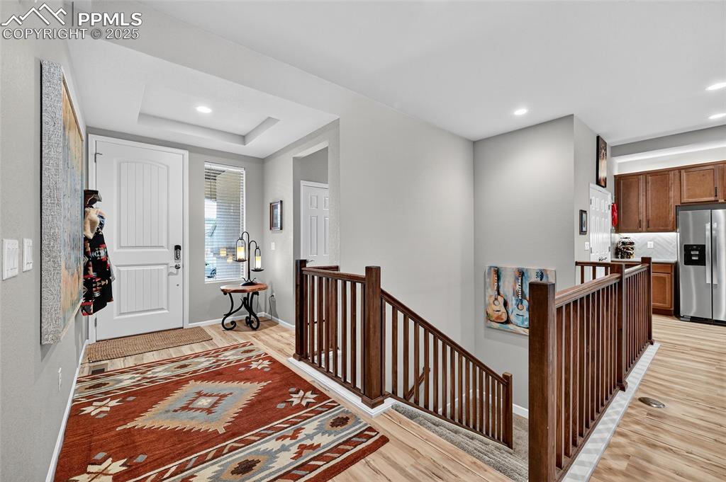 Entryway with light wood-type flooring, recessed lighting, and a tray ceiling