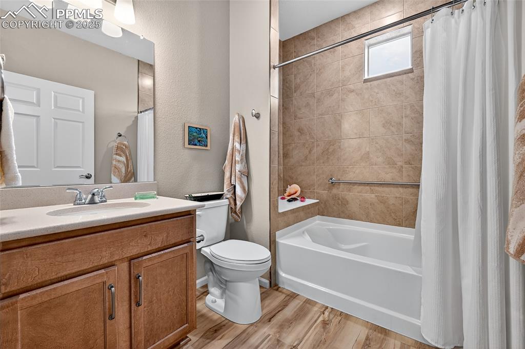 Full bath featuring vanity, a textured wall, shower / tub combo, and light wood-style floors