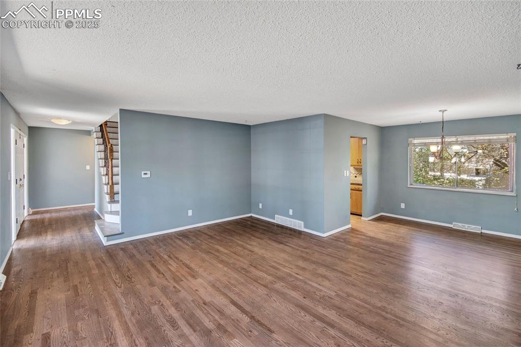 Spare room with dark wood-style floors, visible vents, and a textured ceiling