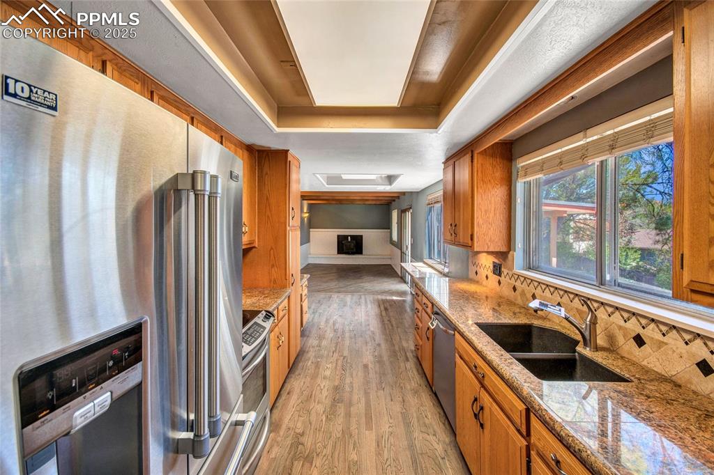 Kitchen with a sink, brown cabinets, light wood-style flooring, decorative backsplash, and appliances with stainless steel finishes