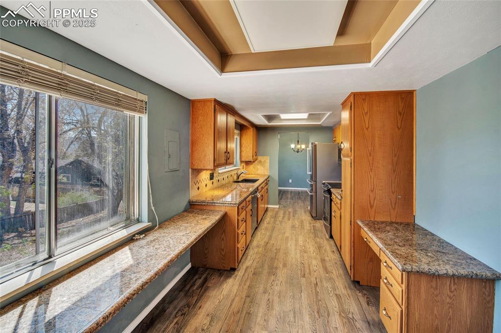 Kitchen with light wood finished floors, brown cabinetry, baseboards, and a sink