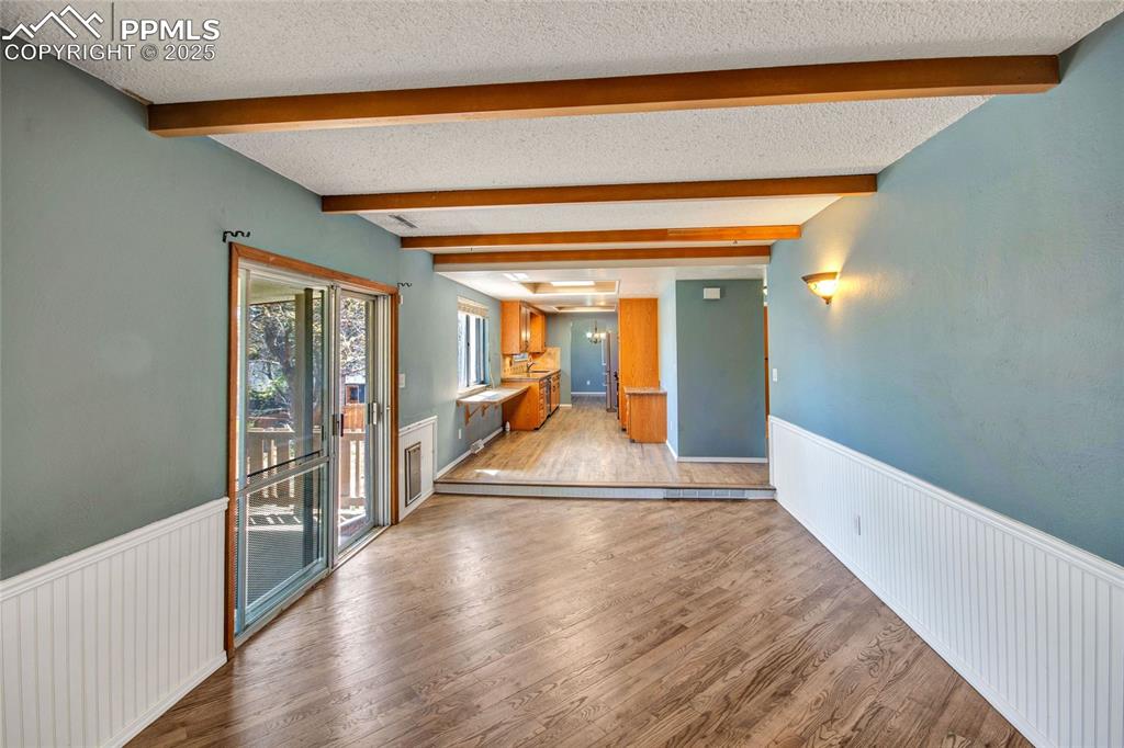 Empty room featuring a textured ceiling, wainscoting, and beamed ceiling