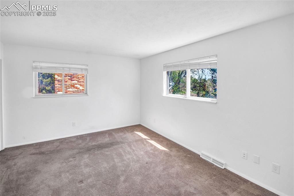 Carpeted spare room featuring baseboards and visible vents