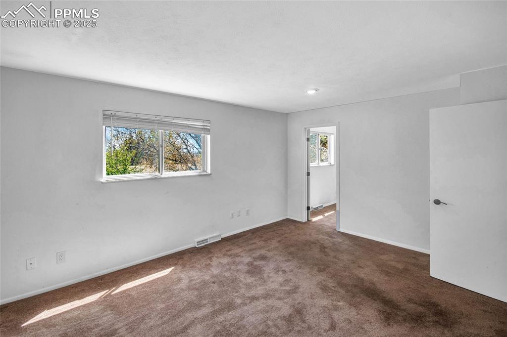 Carpeted empty room featuring baseboards and visible vents