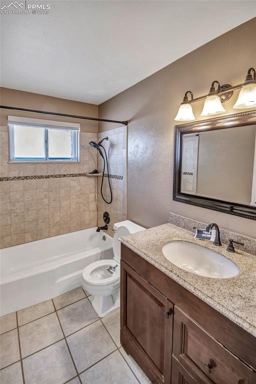 Bathroom with toilet, tile patterned floors, vanity, and shower / washtub combination