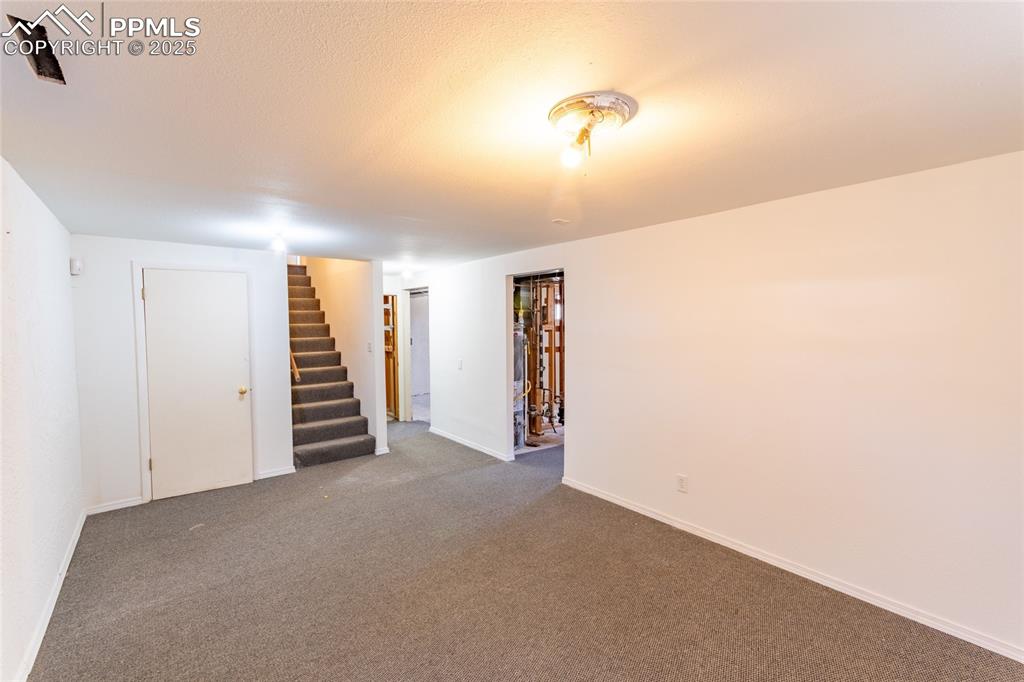 Finished basement with stairway, carpet flooring, and baseboards