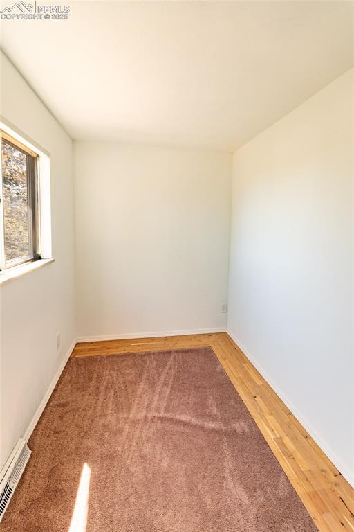 Unfurnished room featuring baseboards, visible vents, and wood finished floors
