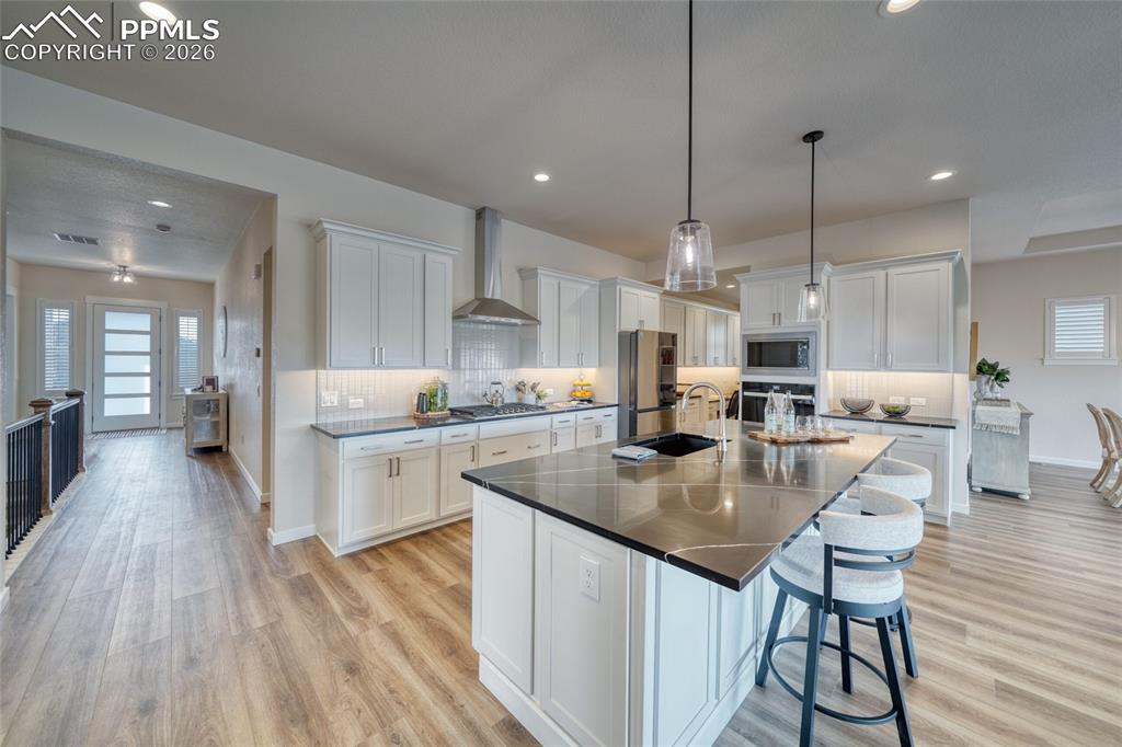 Kitchen featuring white cabinetry, a breakfast bar, decorative backsplash, and light wood finished floors