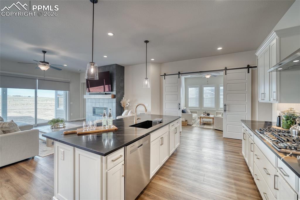 Kitchen featuring a barn door, open floor plan, a ceiling fan, and a tile fireplace