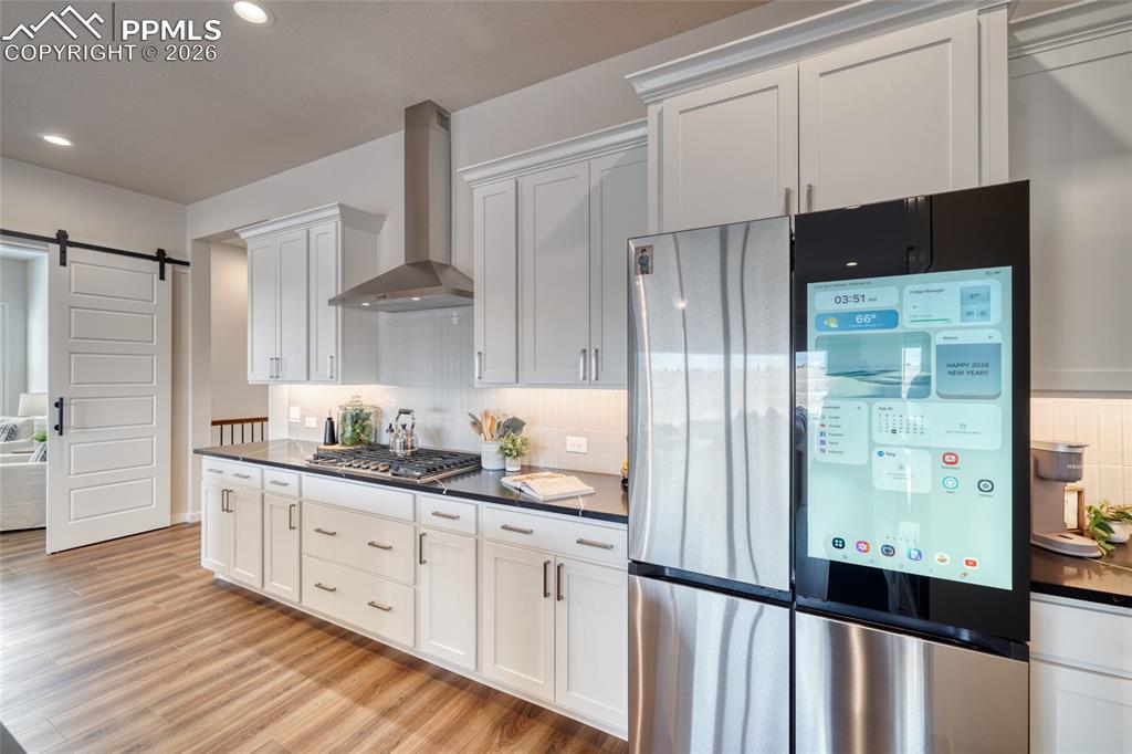 Kitchen featuring stainless steel appliances, a barn door, white cabinets, decorative backsplash, and recessed lighting