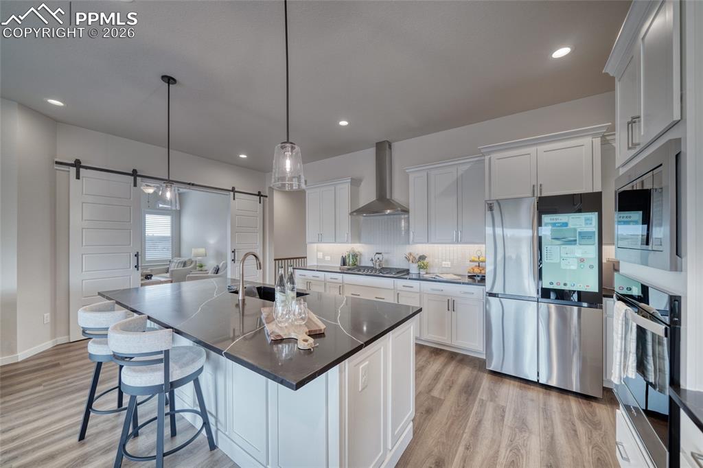 Kitchen with stainless steel appliances, a breakfast bar area, white cabinets, and backsplash