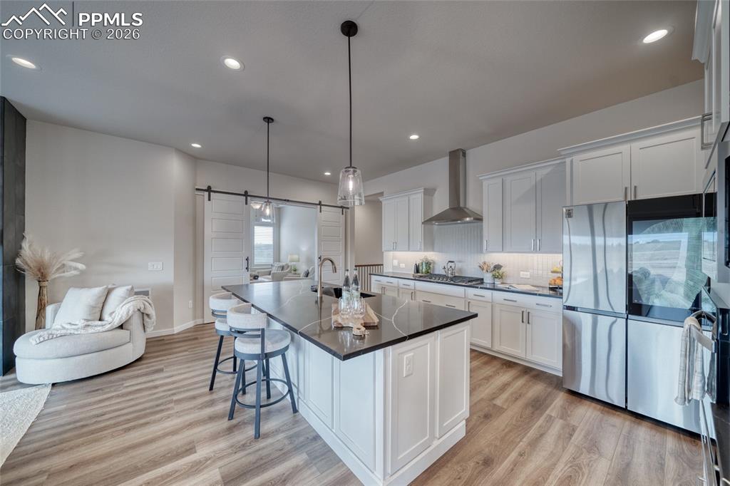 Kitchen featuring a barn door, stainless steel appliances, a breakfast bar, and light wood-style flooring