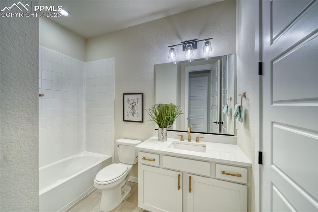 Full bathroom with a textured wall, vanity, bathing tub / shower combination, and recessed lighting