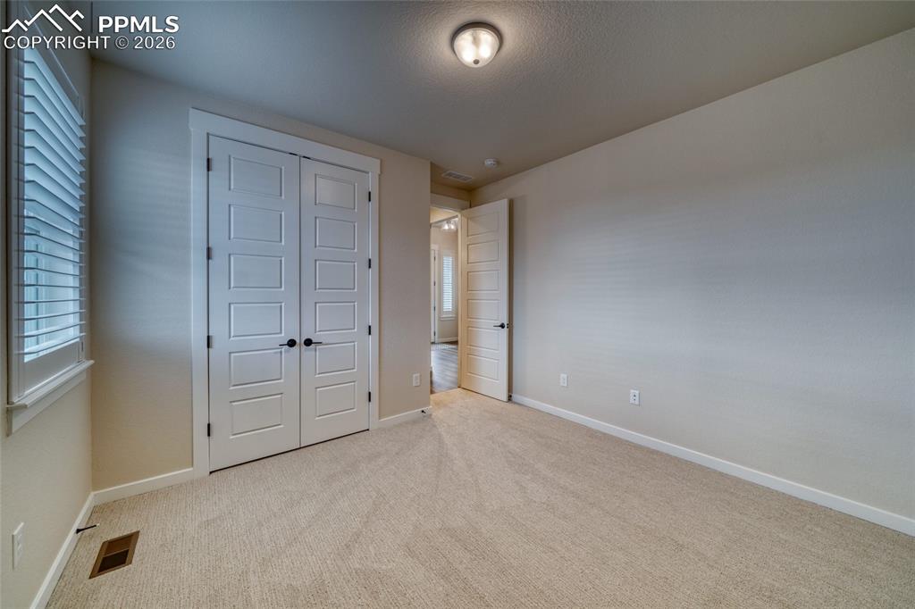 Unfurnished bedroom featuring a closet, light colored carpet, and a textured ceiling