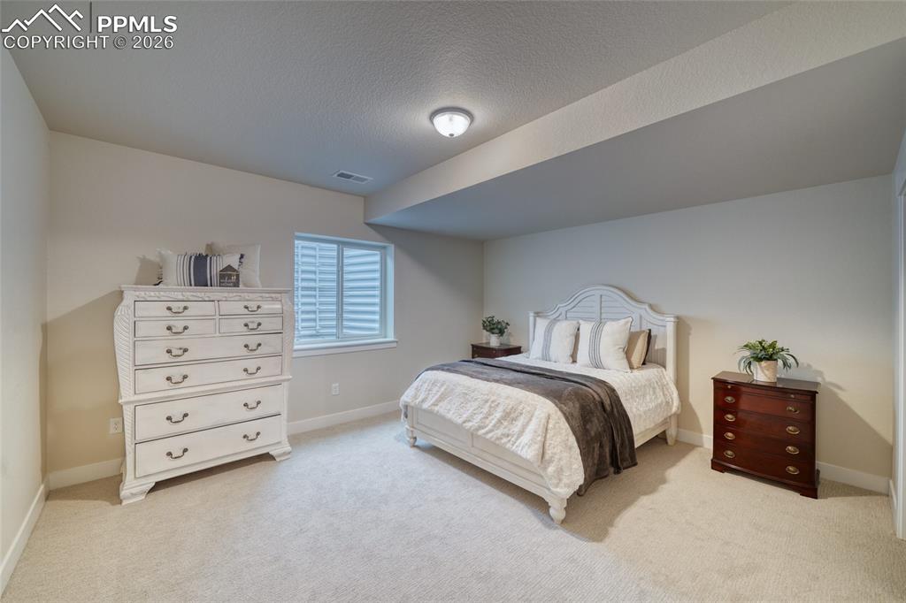 Bedroom with light colored carpet and a textured ceiling