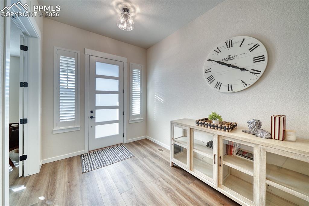 Entryway with light wood-type flooring and a textured wall