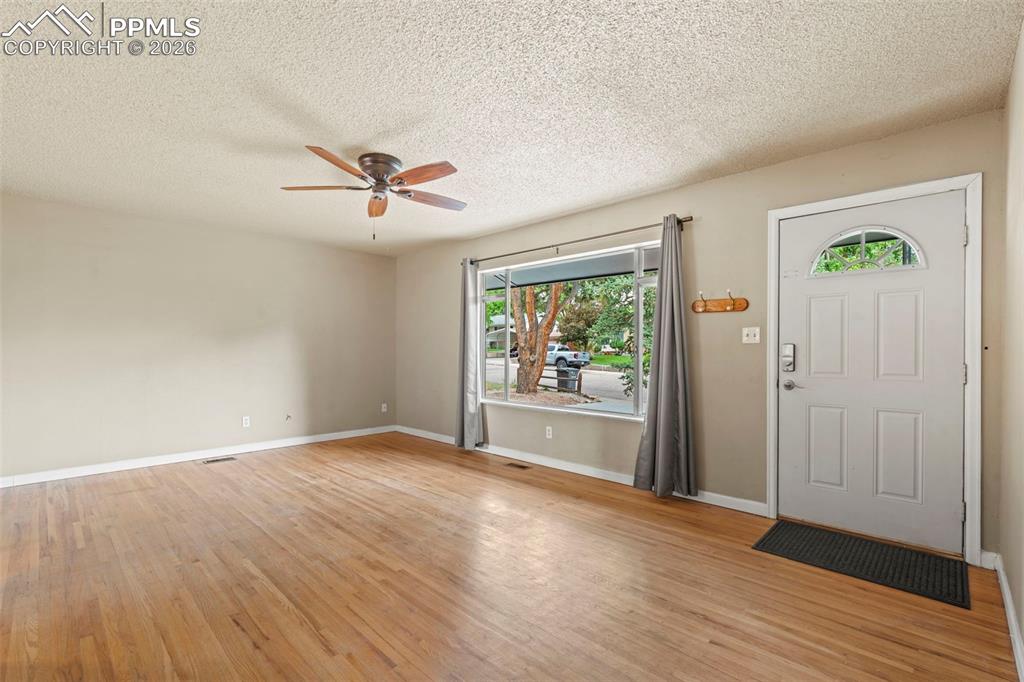 Foyer featuring light wood-style flooring, a textured ceiling, and a ceiling fan