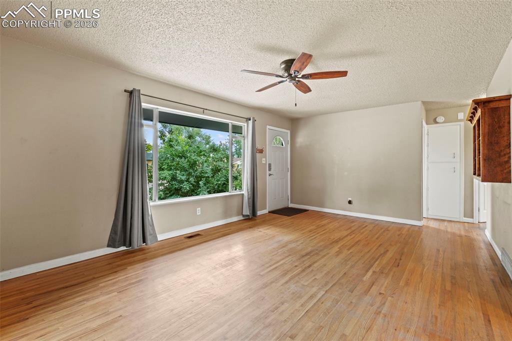 Unfurnished room featuring light wood-style flooring, ceiling fan, and a textured ceiling