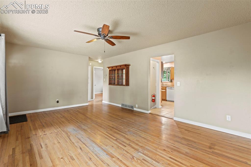 Empty room featuring light wood-type flooring, a textured ceiling, and ceiling fan
