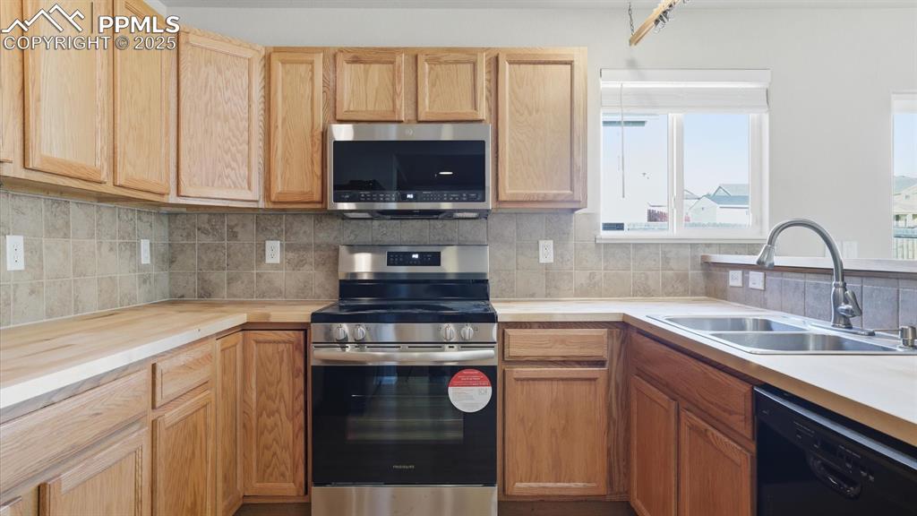 The updated kitchen features a breakfast bar, wood cabinetry topped with new butcher block countertops, and appliances including a  dishwasher, side-by-side refrigerator, and new smooth top range & microwave oven.