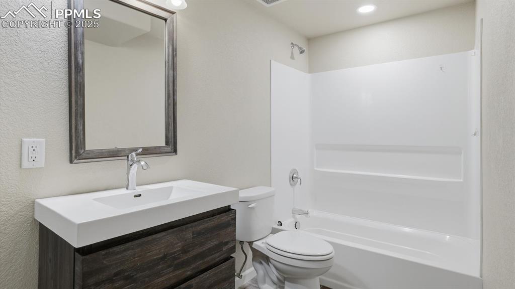 Basement Full Bathroom with vanity, framed mirror, and tiled tub/shower.