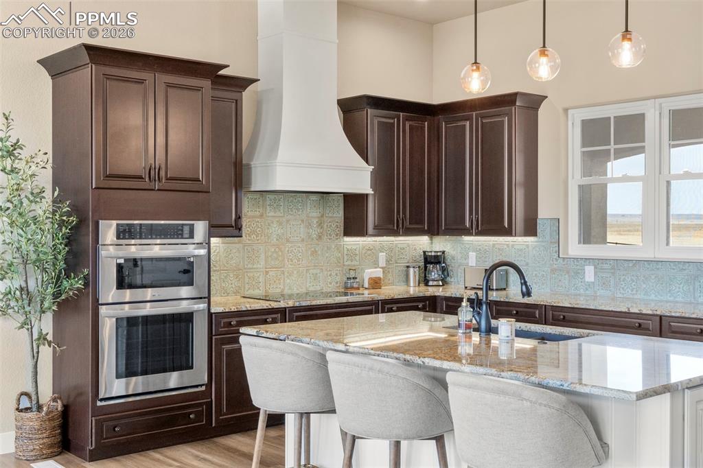 Kitchen features double ovens, breakfast bar, and range hood